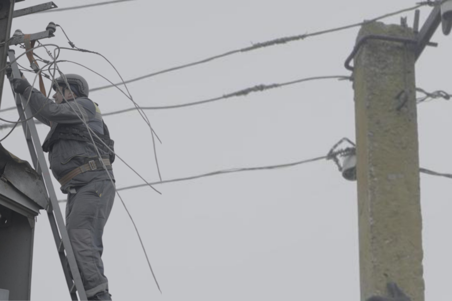 A soldier in grey uniform is working on landline cables in Ukraine.